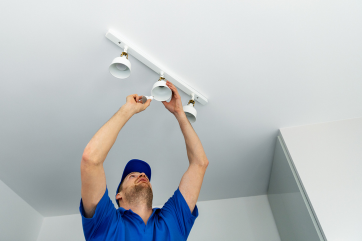 electrician installing led light bulbs in ceiling light fixture