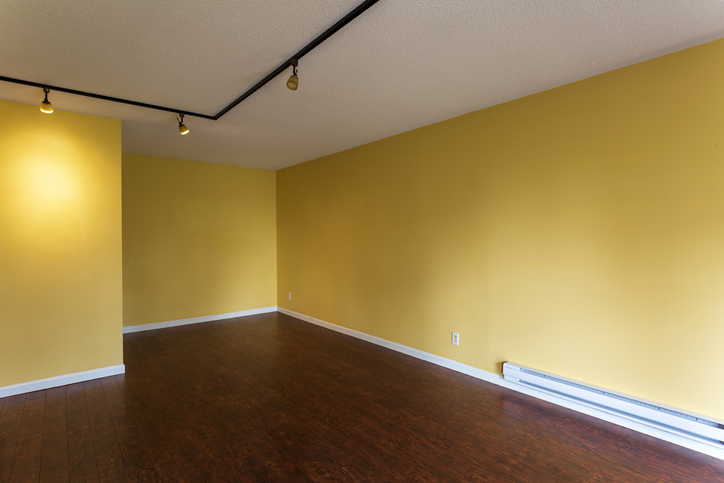 View of empty living room in a modern new apartment condo house interior with empty yellow walls and an electric baseboard heater installed on the wall