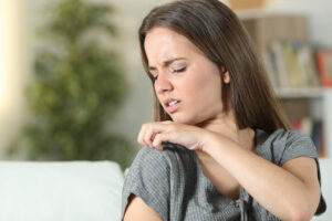 woman with dry winter skin itches her shoulder